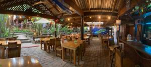 乌蒂拉Mango Inn Resort的一间带桌椅的餐厅和一间酒吧