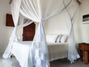 托弗海滩Casa do Índico的卧室内的白色床和天蓬