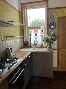 惠特利湾Stunning Whitley Bay apartment的厨房配有水槽、炉灶和窗户。