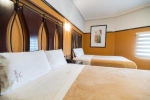 瓜达拉哈拉Hotel Alcazar - Guadalajara Centro Historico的酒店客房设有两张床和窗户。