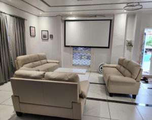 弗里敦Rooftop Villa的客厅配有两张沙发和一个大屏幕