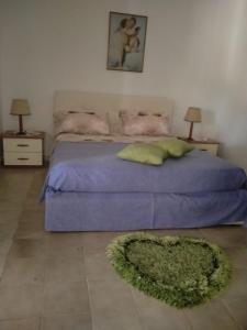 Villa Santa MariaCasa di Giusy的一间卧室配有一张带紫色棉被和绿色地毯的床。