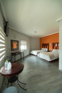 瓜达拉哈拉Hotel Alcazar - Guadalajara Centro Historico的酒店客房设有两张床和一张桌子。