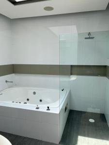 墨西哥城Casa helenico的白色的浴室设有浴缸和玻璃墙