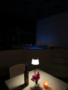 佩里萨特里斯舍尼亚公寓式酒店的桌子上放着一瓶葡萄酒和鲜花,配有一盏灯