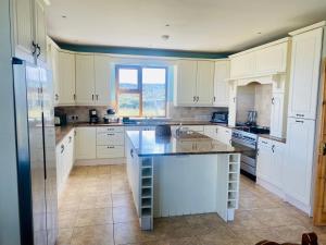 BungowlaIrish Isle Oasis: Spacious 5-Bedroom Retreat的一间厨房,配有白色的橱柜和一个大岛