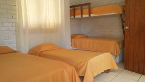 索里托斯Villa Belluno的带3张双层床和橙色床单的客房