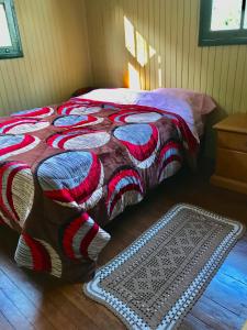 卡内拉Refúgio Linda Vista的一张床上,床上有色彩缤纷的毯子和地毯