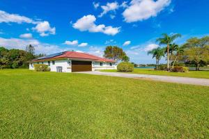 波因顿海滩4/3.5 House with pool- Boynton Beach, FL.的草场上红色屋顶的白色房子