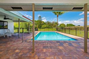 波因顿海滩4/3.5 House with pool- Boynton Beach, FL.的露台的游泳池,带遮阳伞