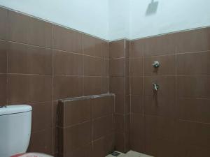 卢武克SPOT ON 92900 Kost 3 Kelor Syariah的浴室设有棕色瓷砖淋浴和卫生间