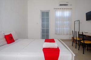 马卡萨RedDoorz at Golden White House Pettarani的卧室配有带红色枕头的大型白色床