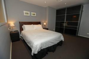 悉尼Har 55 3 bedroom Self-Catering的一间卧室配有一张带白色床单和两盏灯的床。