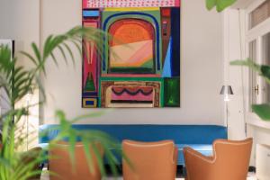 马尔米堡La Serena Hotel FDM的一间设有椅子的房间和墙上的绘画