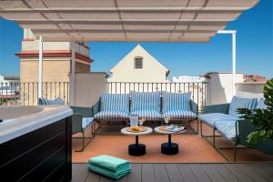 塞维利亚Magno Apartments San Gil - Shared Jacuzzi的阳台的天井配有2把椅子和1张桌子