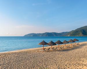 三亚金茂三亚亚龙湾丽思卡尔顿酒店的海滩上的一排遮阳伞和椅子