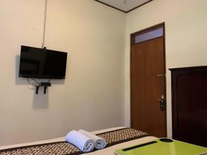 日惹Urbanview Sasono Putro Condoongcatur by RedDoorz的一间设有一张床铺的房间,墙上配有电视