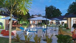 Ban ChamrungPool Villa, Resort, Mae Ramphueng Beach, Ban Phe, Rayong, Residence M Thailand的庭院内一个带椅子和遮阳伞的游泳池