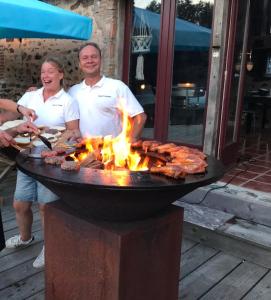 ChiddesGlamping Resort Bousset的站在烧烤炉旁的男人和女人