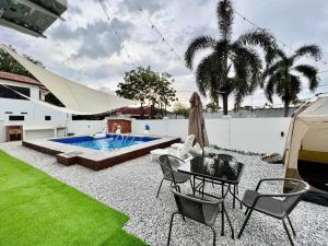 马六甲Klebang Melaka - ADA villa - 12-15pax/4room/Pool的后院设有游泳池、桌子和椅子