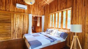 帕干岛Baan Bhuwann Forest Chalet的木制客房内的一间卧室,配有一张床