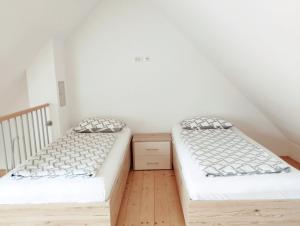 博维茨Apartments Wallas的配有白色墙壁和木地板的客房内的两张床