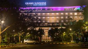 万隆Grand Sunshine Resort & Convention的夜间停在大楼前的汽车