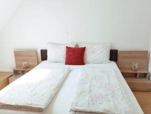 博维茨Apartments Wallas的一张带白色床单和红色枕头的床