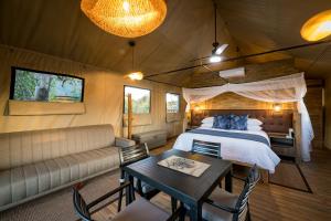斯库库扎Nkuhlu Tented Camp的一间卧室配有一张床、一张桌子和一张沙发
