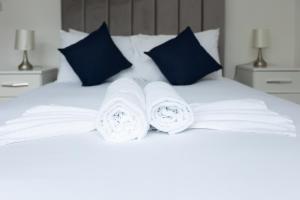 伦敦Imperial liverpool street apartments的一张白色的床,上面有3条滚毛巾