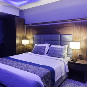 阿可贺巴Swat Hotel Apartments 2的一间卧室配有一张大床和两盏灯。