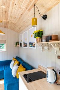 巴拉特Enchanting Tiny House with wood burner and hot tub in Cairngorms的客厅设有蓝色的沙发和木制天花板。