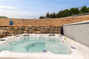 巴拉特Enchanting Tiny House with wood burner and hot tub in Cairngorms的后院的热水浴池,设有石墙