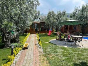 İznikTiny House Village的花园配有桌椅和遮阳伞。