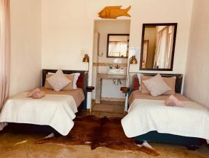 DivunduKuvira River Camp的配有镜子和水槽的客房内的两张床