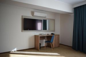 布拉索夫雷格尔酒店的一间房间,配有一张桌子和一台墙上的电视