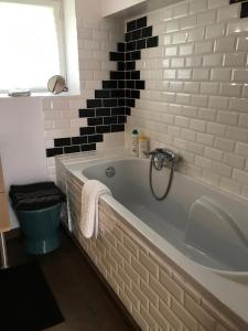 滨海图维列La Maison Rouge的浴室设有白色浴缸和黑色瓷砖。