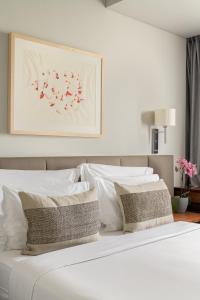 里斯本多卡洛斯公园酒店的白色的床铺、白色的枕头和墙上的绘画