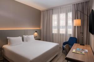 的里雅斯特NH特里斯特酒店的配有一张床、一张书桌和一扇窗户的酒店客房