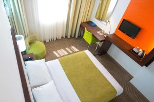 卢萨卡StayEasy Lusaka的酒店客房配有一张床、一张书桌和一台电视。