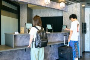 大阪COGO TENNOJI的两个人带着行李站在柜台