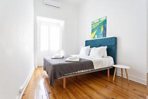 塔维拉Alagoa Apartments的白色卧室,配有一张蓝色床头板的床