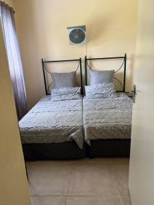 贝拉贝拉Pendleberry Holiday Resort - Unit 41的一张带两个枕头的床和墙上的时钟