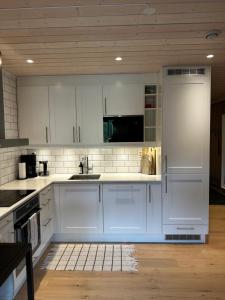 耶卢Fin leilighet på Geilotunet leies ut的厨房配有白色橱柜和水槽
