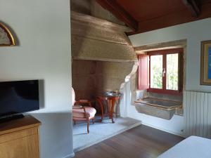 VillamarínCasa das Capelas的客厅设有石制壁炉和电视。