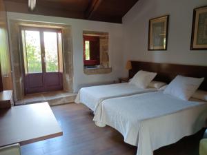 VillamarínCasa das Capelas的一间设有两张床、一个窗口和一扇门的房间