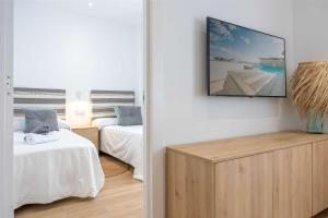 马罗APARTAMENTOS CARMEN的客房设有两张床和一台墙上的电视。