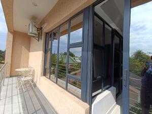 哈博罗内Manasseh Guesthouse的阳台设有玻璃门和桌椅。