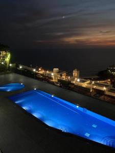 塔乌里托Stunning sunset ocean view apt.的夜间建筑物屋顶上的蓝色游泳池