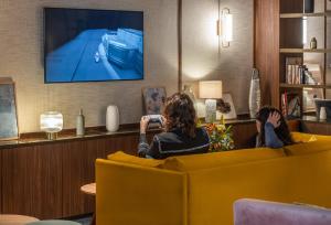 波尔多Hôtel Burdigala by Inwood Hotels的两个女人坐在沙发上看电视